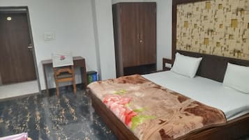 Ein Hotelzimmer mit einem Bett, einem Schreibtisch, einem Kleiderschrank und einem gemusterten Kopfteil.