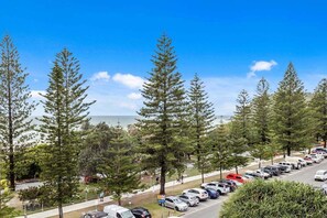 A parking lot with cars, trees, and a clear sky. - Iconic Burleigh Beachfront, 2 Bedroom Apartment (Gold Coast)