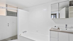 A modern bathroom with a walk-in shower, a bathtub, and a vanity with a mirror. - Iconic Burleigh Beachfront, 2 Bedroom Apartment (Gold Coast)
