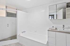 A modern bathroom with a walk-in shower, a bathtub, and a vanity with a mirror. - Iconic Burleigh Beachfront, 2 Bedroom Apartment (Gold Coast)