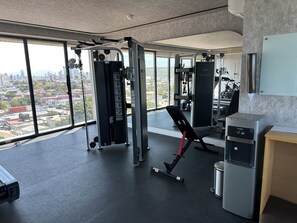 A gym with exercise equipment, a bench, and a water dispenser. - Sleek Modern Condo in Downtown Tijuana - Free Parking, 24/7 Security, and Rooftop (Tijuana)