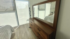 A bedroom with a large mirror, a wooden dresser, a bed, and a sliding glass door. - Sleek Modern Condo in Downtown Tijuana - Free Parking, 24/7 Security, and Rooftop (Tijuana)