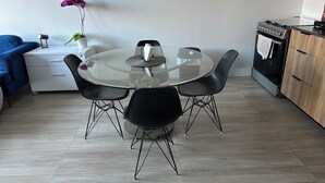 A modern kitchen with a round glass table, black chairs, a blue sofa, and a potted orchid. - Sleek Modern Condo in Downtown Tijuana - Free Parking, 24/7 Security, and Rooftop (Tijuana)