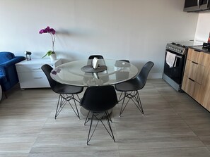 A modern kitchen with a round glass table, black chairs, a blue sofa, and a potted orchid. - Sleek Modern Condo in Downtown Tijuana - Free Parking, 24/7 Security, and Rooftop (Tijuana)