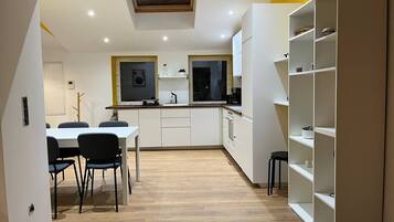 Een moderne keuken met witte kasten, een eettafel met stoelen en een inbouwboekenkast.