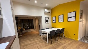 A modern kitchen with a dining area, wooden flooring, and a bright yellow accent wall. - La Botte - 2-Bedroom Apartment, Downtown Épinal (Épinal)