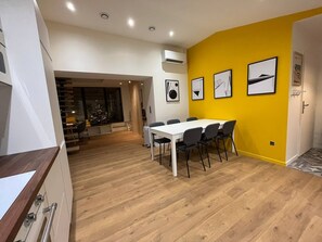 Une cuisine moderne avec un coin repas, un plancher en bois et un mur d’accent d’un jaune vif.