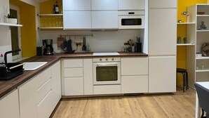 A modern kitchen with white cabinets, a wooden countertop, and a built-in oven. - La Botte - 2-Bedroom Apartment, Downtown Épinal (Épinal)