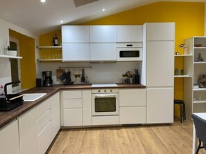 Une cuisine moderne avec des armoires blanches, un plan de travail en bois et un four encastré.
