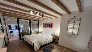 A bedroom with a bed, wooden floor, a mirror, and a small rug. - La Botte - 2-Bedroom Apartment, Downtown Épinal (Épinal)