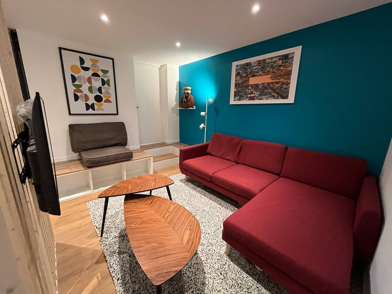 Una sala de estar moderna con un sofá rojo, una mesa de centro de madera y una pared azul de acento.