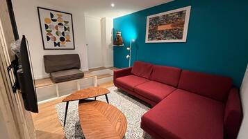 Una sala de estar moderna con un sofá rojo, una mesa de centro de madera y una pared azul de acento.