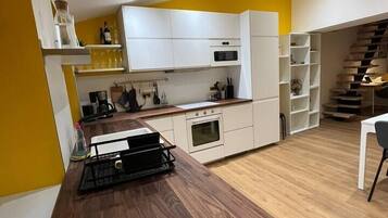 Una cocina moderna con armarios blancos, encimera de madera y horno empotrado.
