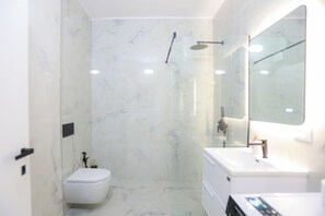 A modern bathroom with a shower, toilet, and sink. - Sea Side Palm Modern Suites (Orikum)