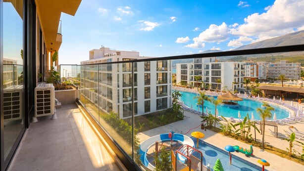 Ein Balkon mit Blick auf einen Swimmingpool und angrenzende Gebäude.