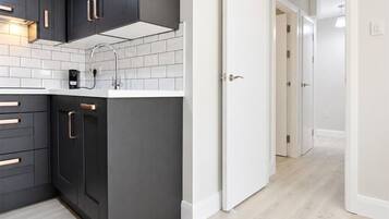 Una cocina moderna con armarios oscuros, azulejos blancos tipo metro y piso de madera clara.