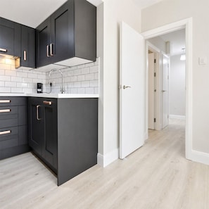 A modern kitchen with dark cabinetry, white subway tiles, and a light wood floor. - Modern Central Dublin Apartment  Near Bolton Square (Dublin 1)