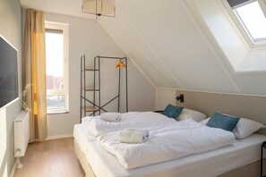 Ein Schlafzimmer mit einem Bett, einem Heizkörper, einem Fenster mit Vorhängen und einem Oberlicht.