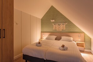 A bedroom with a bed, a nightstand, a wooden wardrobe, and a patterned wall. - Stay Near the Waters (Bruinisse)