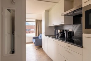 A modern kitchen with white cabinets, a black countertop, and a coffee maker. - Stay Near the Waters (Bruinisse)