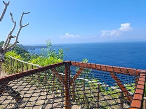 A rope bridge leading to a scenic overlook with a view of the ocean. - Suwehan Rey Cliff House (Penida Island)