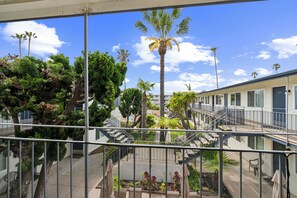 A hotel with a balcony, palm trees, and a clear blue sky. - Lovely 1-bedroom condo in Carpinteria steps from the beach (Carpinteria)