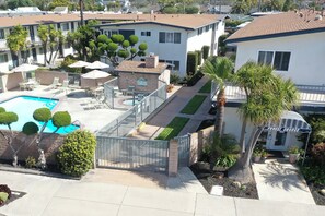 A residential area with a swimming pool, fenced patio, and a building labeled "Sunset Shores." - Lovely 1-bedroom condo in Carpinteria steps from the beach (Carpinteria)