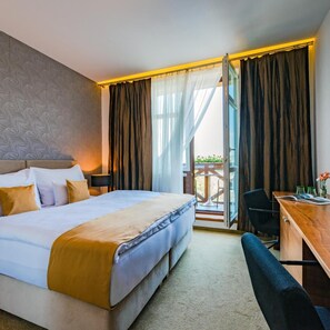 A hotel room with a bed, desk, and a view of the outdoors. - Hotel Restaurant Vetruse (Usti nad Labem)