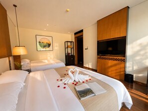 Habitación de hotel con dos camas, televisión, estantería y un cuadro en la pared.