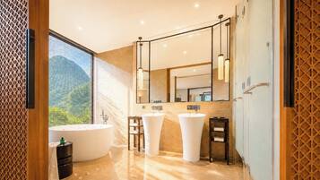 A modern bathroom with a large bathtub, two sinks, a vanity, and a large mirror.