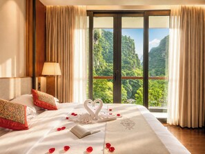 A hotel room with a large bed, a view of a mountainous landscape, and a balcony with curtains. - The Blossom Dreamscape Boutique Hotel - Yulong River Branch - Free Buffet Breakfast & Laundry Facilities & Tailor Made Tours  (Guilin)