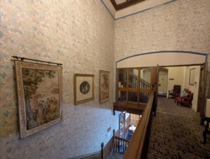 A room with patterned wallpaper, a staircase, and a view of another room with furniture. - Superior Double or Twin Room (Burton on Trent)
