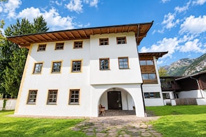 A multi-story building with a white facade and multiple windows, set against a backdrop of mountains and a clear sky. - Chalet in Angerberg Near Skiwelt Slopes (Angerberg)