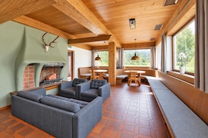 A cozy interior with a fireplace, seating area, and large windows offering a view of the outdoors. - Chalet in Angerberg Near Skiwelt Slopes (Angerberg)