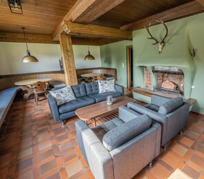 A cozy living room with a brick fireplace, wooden beams, and a stone-tiled floor. - Chalet in Angerberg Near Skiwelt Slopes (Angerberg)