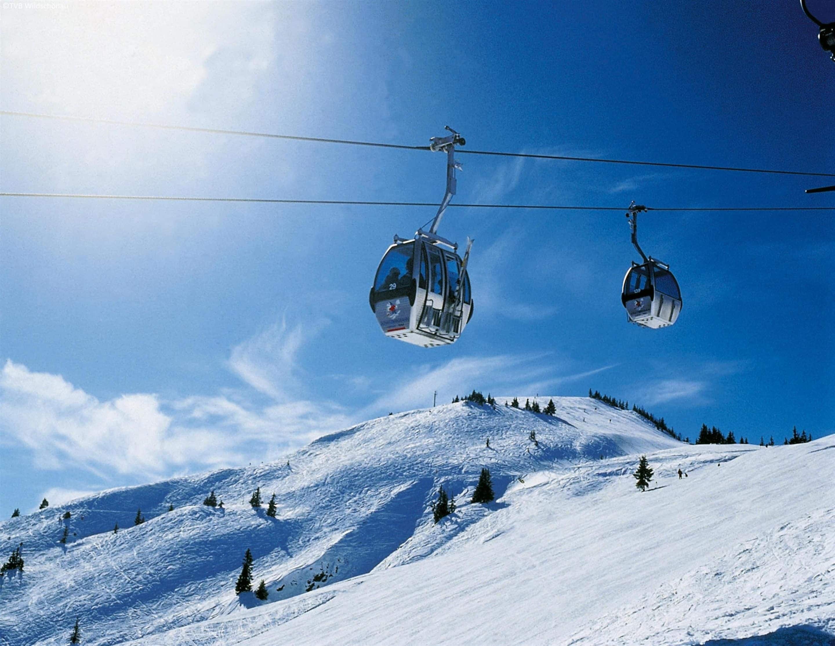 A ski lift with cabins suspended from cables against a clear blue sky.