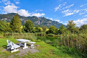 A picnic table with benches in a grassy area with a lake and mountains in the background. - Chalet in Angerberg Near Skiwelt Slopes (Angerberg)