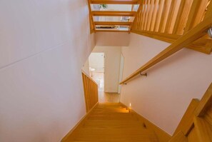 Eine Holztreppe mit Handlauf, die zu einer oberen Ebene führt.