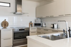 Eine moderne Küche mit Edelstahlgeräten, weißen Schränken und einem eingebauten Backofen.
