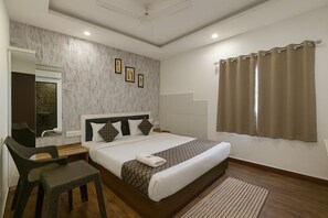 A hotel room with a bed, a desk with a chair, a mirror, and a window with curtains. - Hotel Seasons- Indore (Indore)
