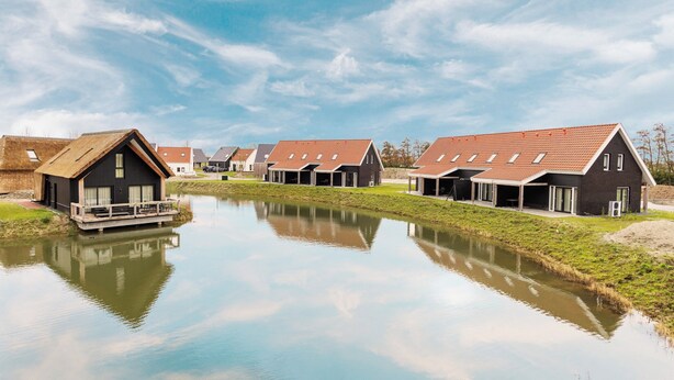 Eine Reihe moderner Häuser mit einem Kanal im Vordergrund.