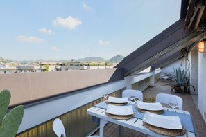A balcony with a table set for two, overlooking a cityscape with mountains in the distance. - Comosette - Outdoor Dining/Outdoor Relax/Central  (Como)