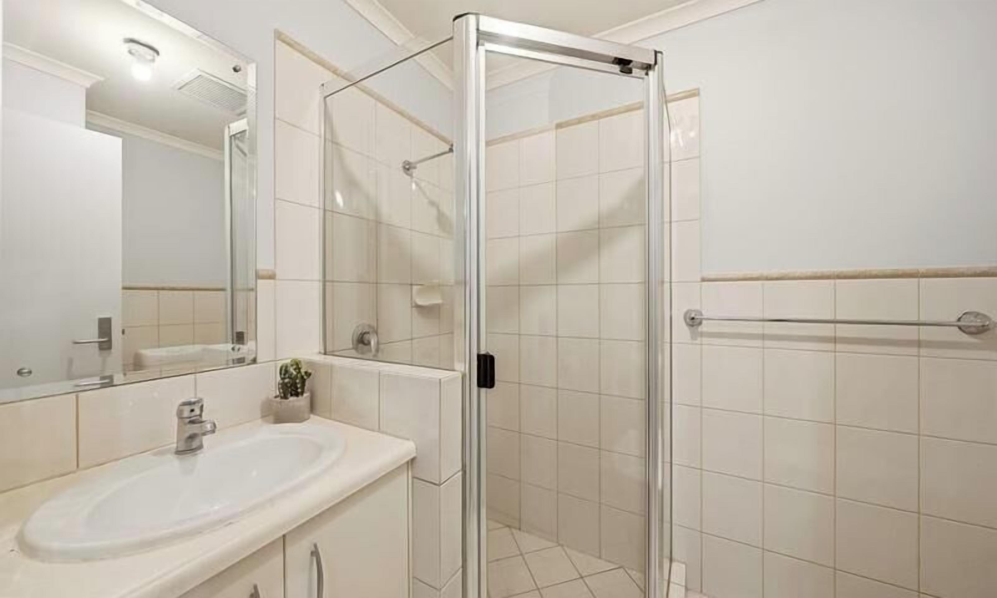 Ein Badezimmer mit einer Duschkabine, einem Waschbecken und einem Spiegel.