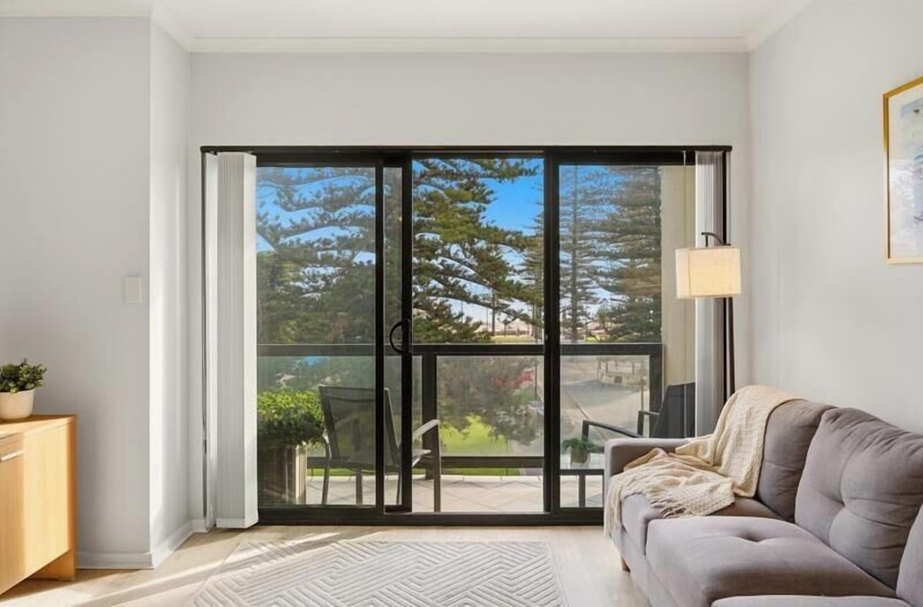 A room with a sliding glass door leading to an outdoor area, a sofa, a small table, and a lamp.