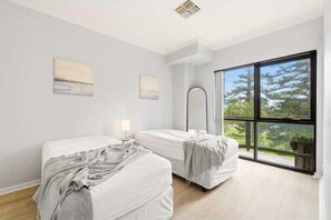 Ein Zimmer mit zwei Betten, einem großen Fenster und Blick auf Bäume.