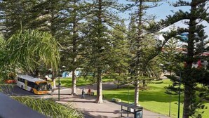 A bus stop with a bench, a bus, and trees in a park setting. - Belle Escapes - Bayview Escape Glenelg (Holdfast Bay)