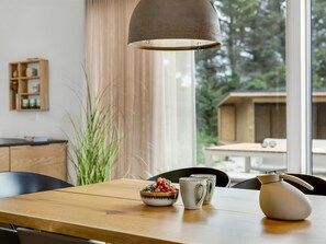 A dining area with a wooden table, a bowl of fruit, a mug, and a kettle. - "Huldrik" - 900m from the sea by Interhome (Løkken)