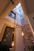 Un interior moderno con pared de piedra, tragaluces y lámparas colgantes.