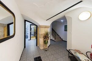 Un pasillo con piso estampado, una escalera y un espejo a la izquierda.
