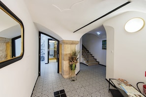 A hallway with patterned flooring, a staircase, and a mirror on the left. - APLEND Paul Inn (Bratislava)